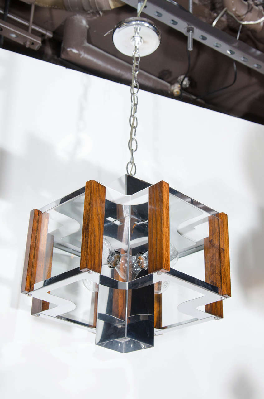 Vintage ultra modernist chandelier with quadrilateral form. The fixture has a polished chrome metal frame with walnut wood trim details, and glass square panels. The chandelier is comprised of a square cylinder center stem with four architectural