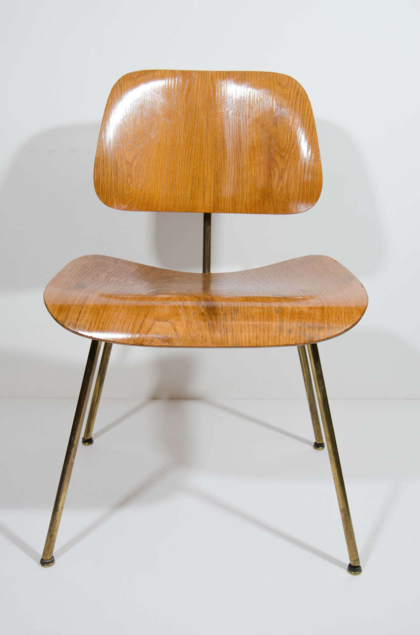 Set of four original bent and molded plywood chairs with exceptional modern Industrial Design. The iconic design made for The Herman Miller Company is comprised of ash wood seats, with patinated brass frame and legs. The chairs have rubber mount