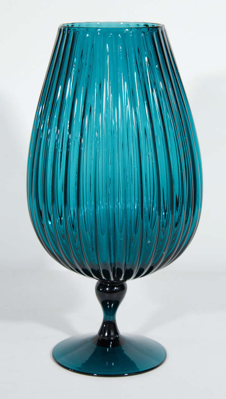 Tall handblown vase with modernist urn form and footed base design. The vase has fluted details along the sides and has a beautiful vintage teal hue.