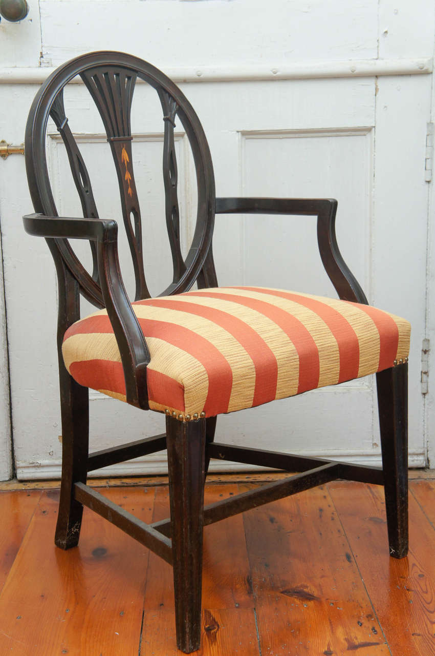 Hepplewhite-style ebonized open-armed chair, circa 1880. Burnished bellflower
decoration on back center rail. Quadrille red and yellow striped fabric on
tight upholstered seat, finished with upholstery tacks.