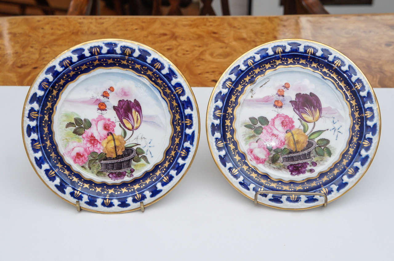 Pair of small Vieux Paris plates with tulips and roses
decorating the center. Deep blue surround with gold
details.