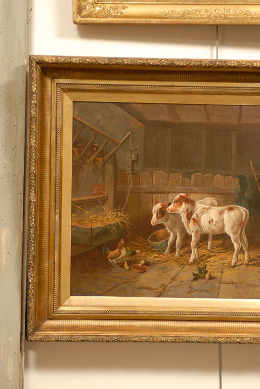 An English 19th century oil on canvas painting depicting farm animals in a barn in giltwood frame. This English farm painting features two lovely calves that seem to be hesitantly standing on their young legs, walking towards a trough full of hay