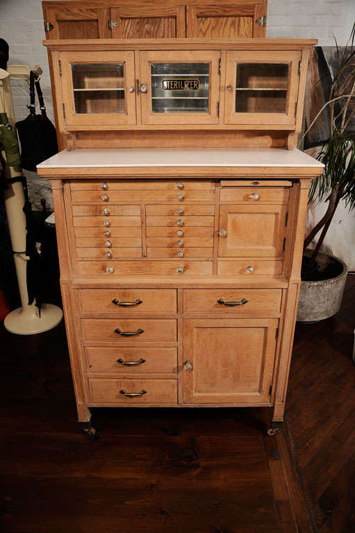 Vintage all original dental cabinet. The workmanship that went into the cabinet is fine in every detail. Milk glass shelf for the tops are included. <br />
<br />
The cabinet retains the original glass pulls on the drawers in perfect condition.