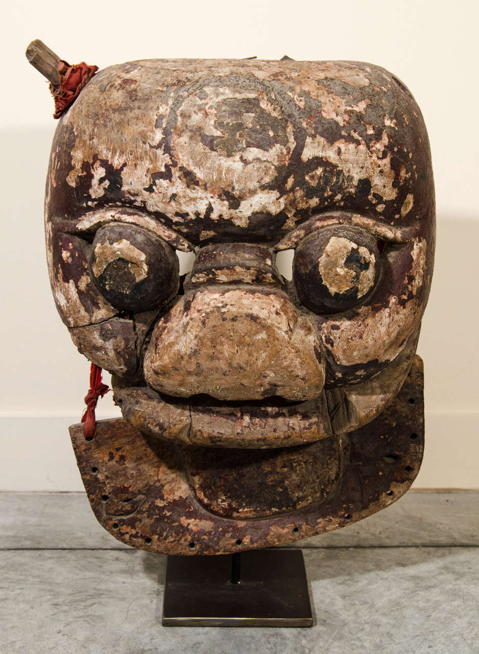 A striking 18th Century poplar wood Chinese mask, with traces of original paint. Mounted on custom iron stand.  From Shanxi Province, late 18th Century.
M615a