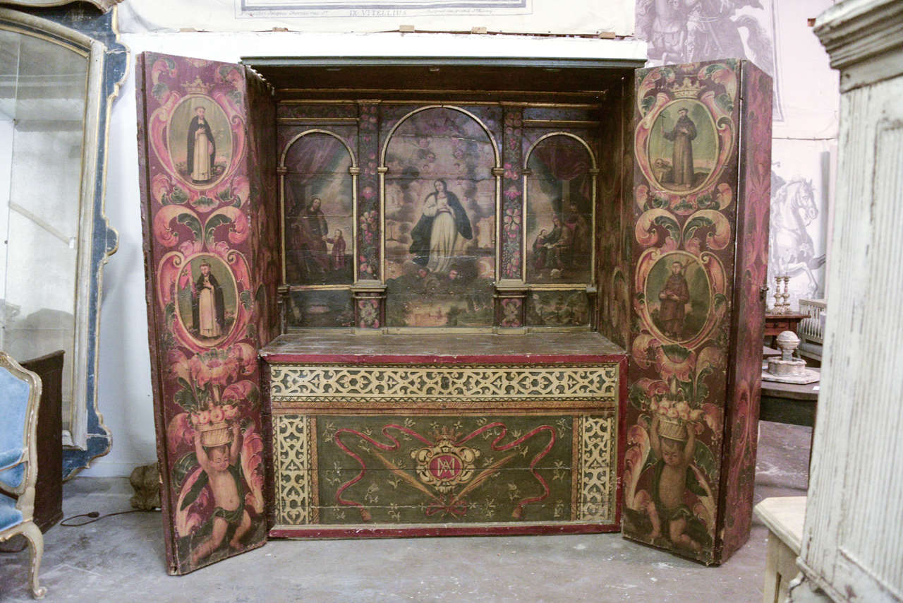 18th century Spanish campaign altar with paintings of saints and cherubs.
the altar closes like an armoire;