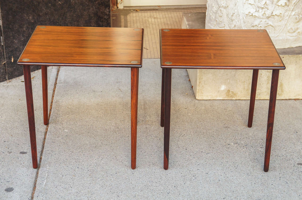 Pair of Early 1960s Danish Low Tables of Finely Figured Rosewood.  The legs joined through the table top and ending in polished brass caps.  Note:  Two Pairs are available.