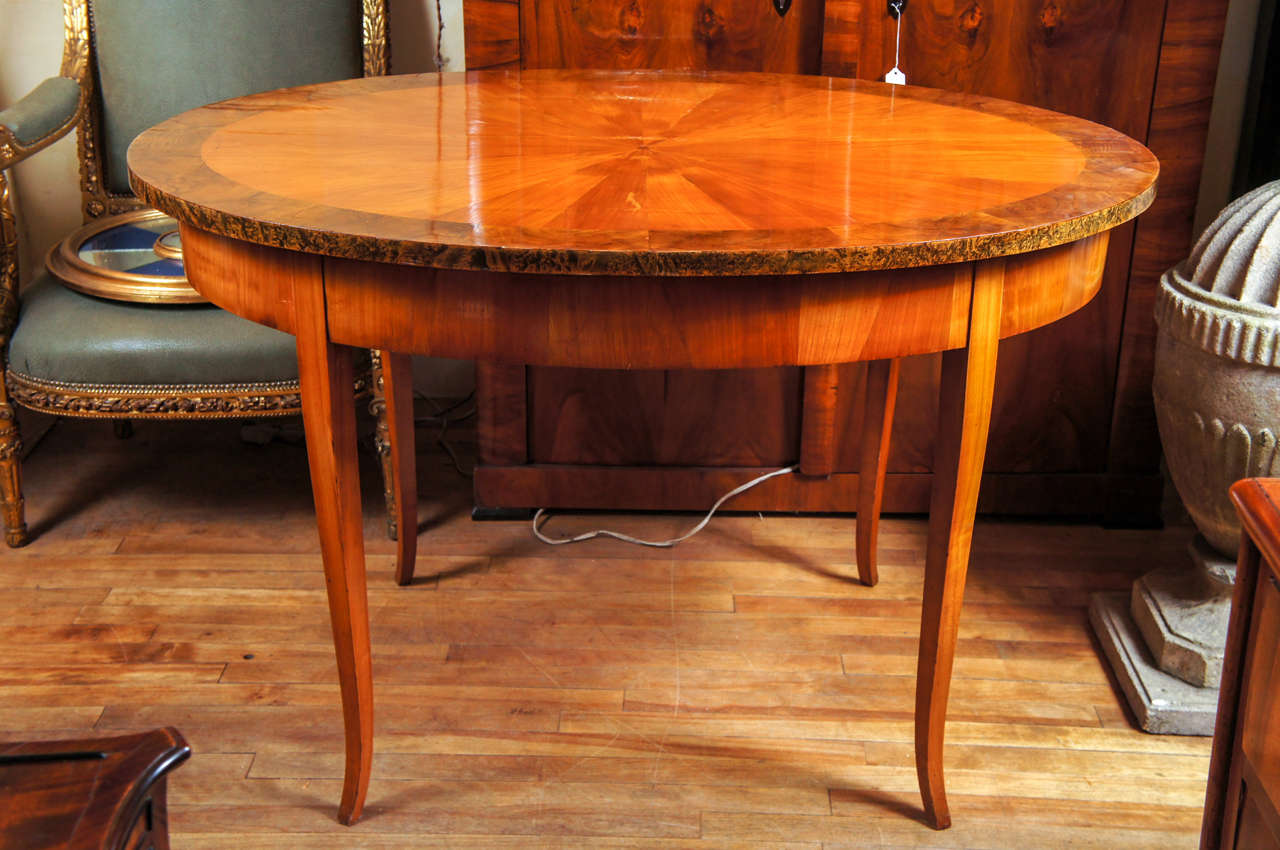 This 19th century elongated oval center table has a pleasing form with delicate proportions. The Austrian table is decorated with a veneered top of pie shaped wedges of Fruit wood light in color centered on a small walnut circle that has been banded
