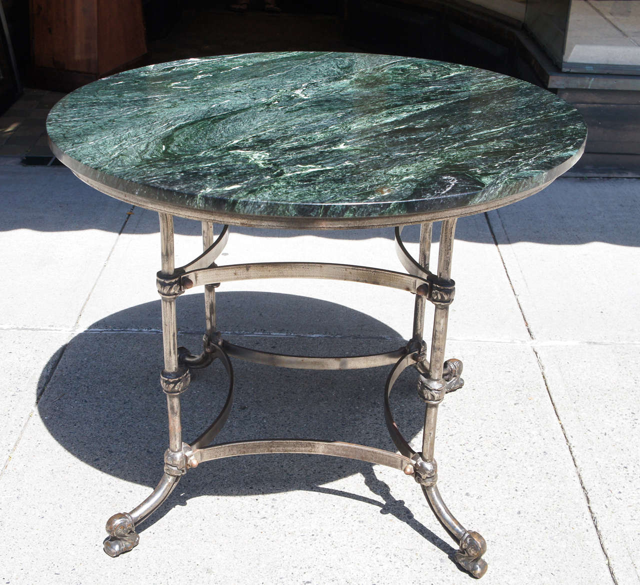 This late 19th century table could be used as a breakfast , center or large occasional table. Made in an industrial way the steel is hand wrought and held together with large exposed brass nuts and bolts giving the table a masculine textural style.