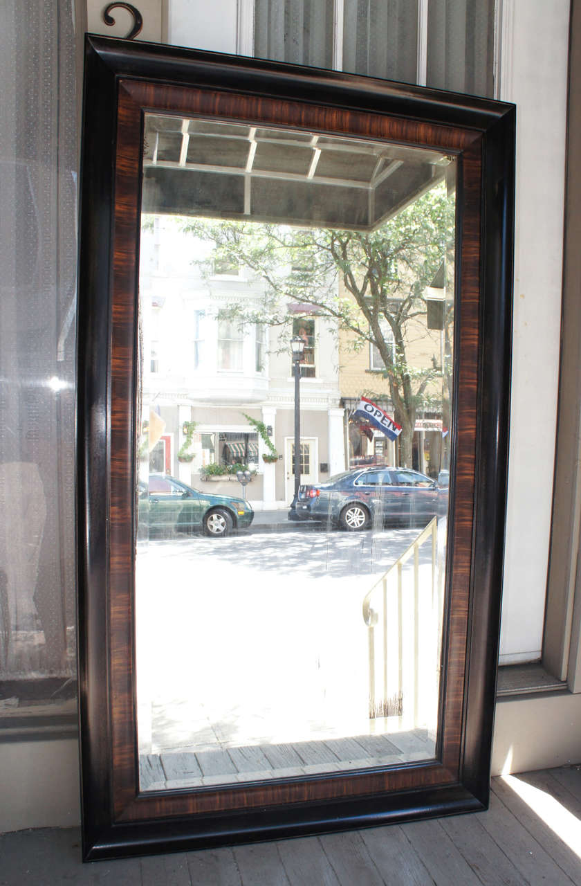 This masculine grain painted mirror frame is composed of two separate frames. The inner frame is grained rosewood in deep long strokes creating a pattern around the mirror and the second outer large and the deeper frame is ebonized and shows some