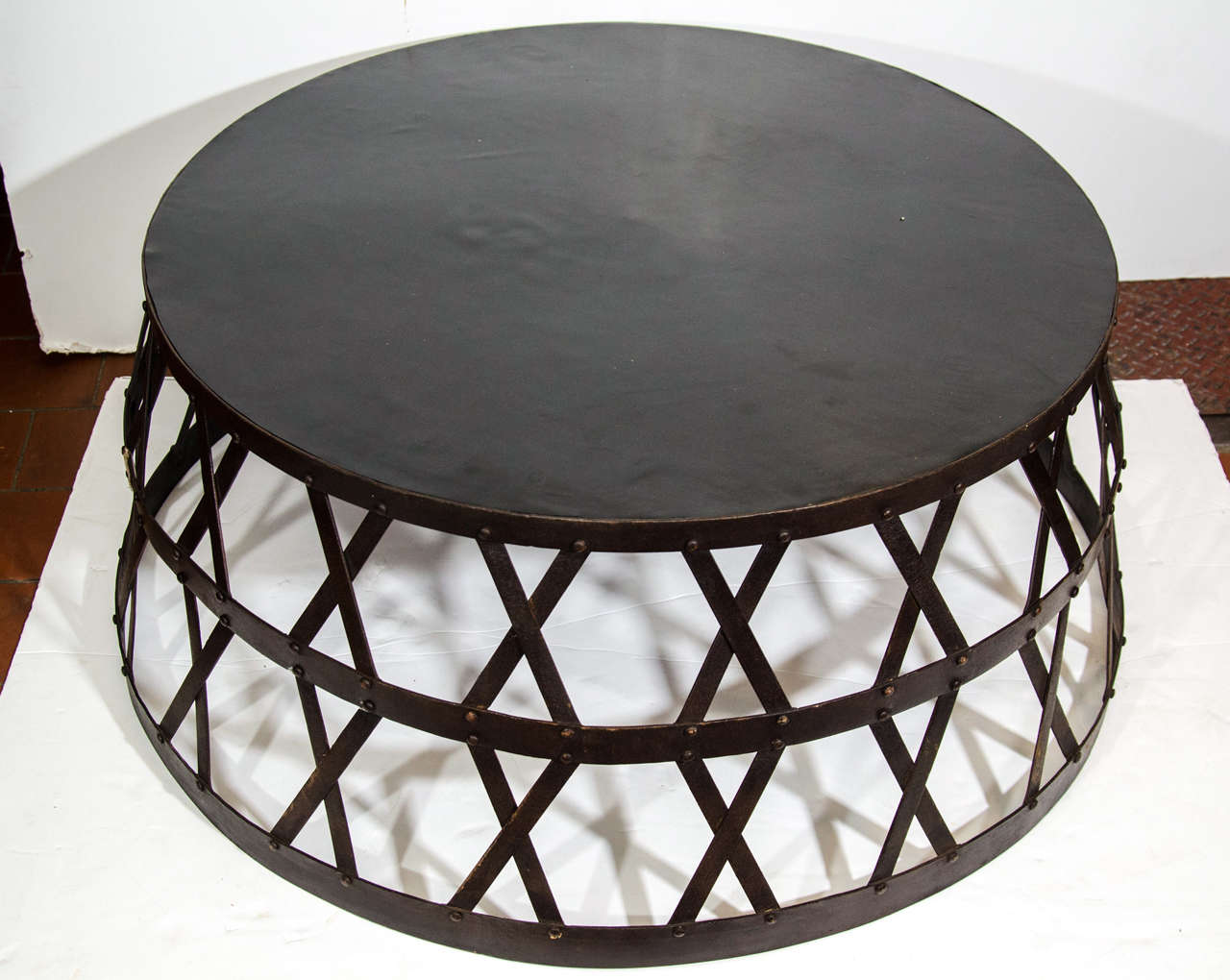 Elephant drum table with rubber top and a metal crisscross design.