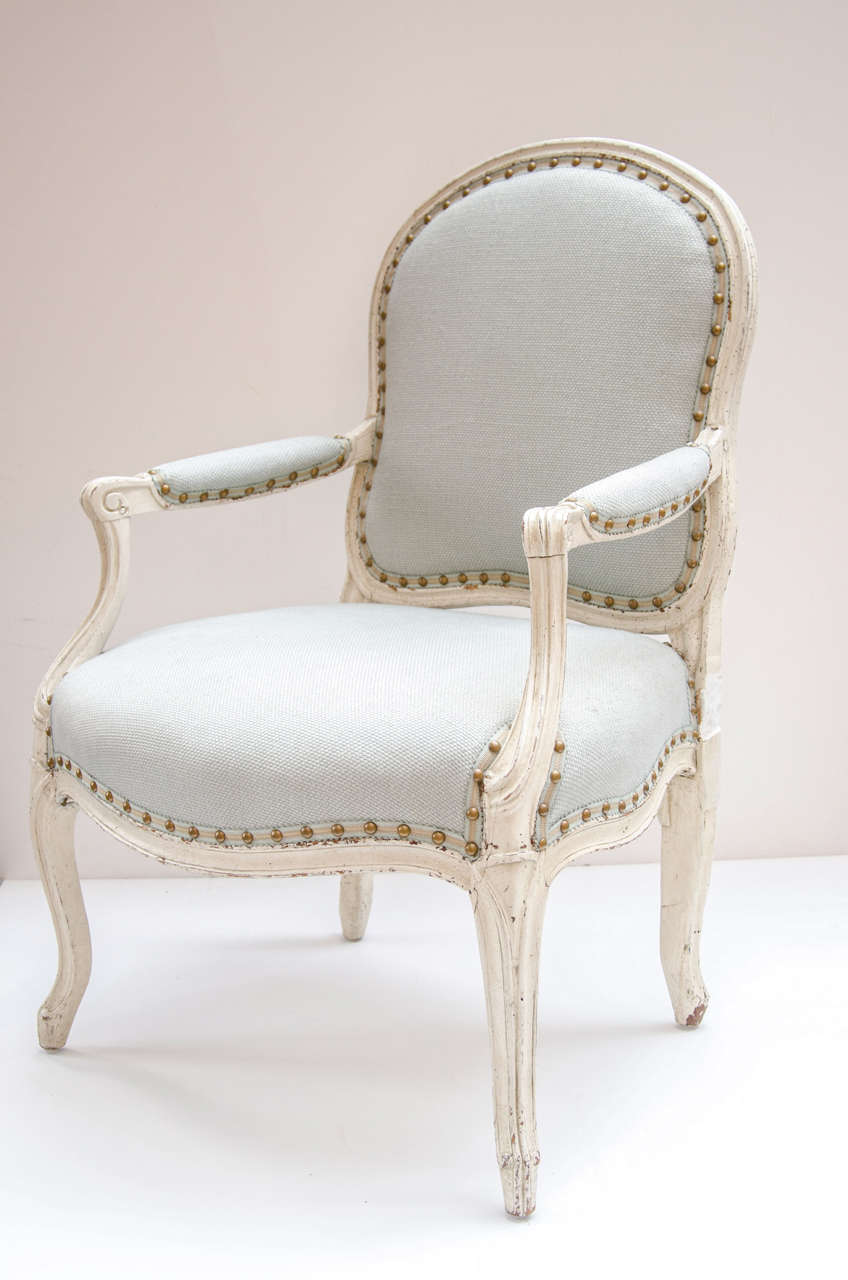 Pair of elegant Provincial armchairs with hand-carved wood frame and white wash finish. The chairs have been newly upholstered in fine pale sea foam linen by Manuel Canovas. The chairs also feature hand-hammered nailhead details. The back of the