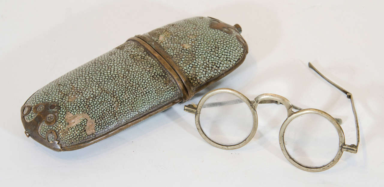 A pair of traditional antique Chinese eyeglasses with folding stems, together with a green shagreen eyeglass case, 
China, circa 1900
M1003.