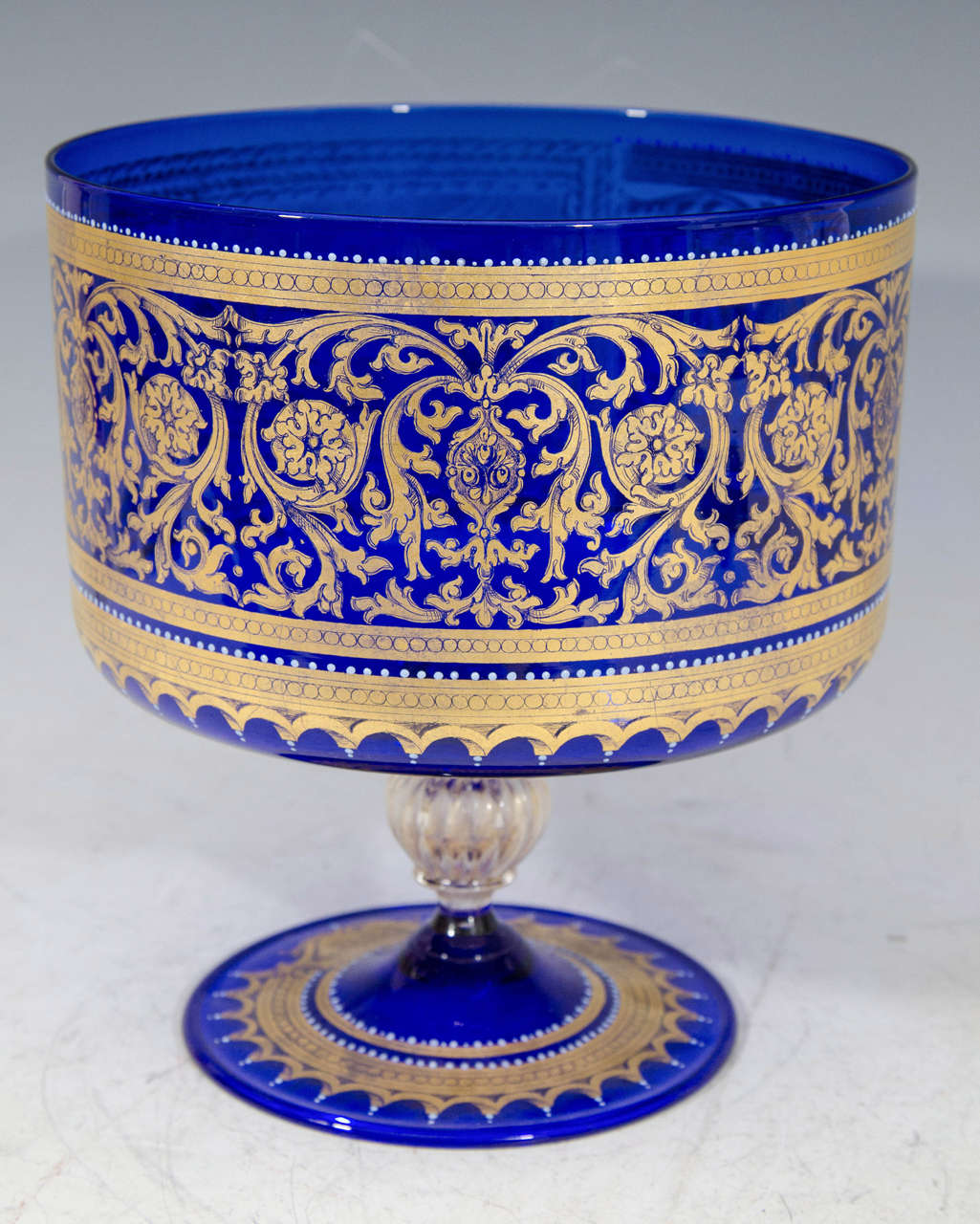 A cobalt Venetian Murano glass footed bowl or compote with hand-painted baroque style scene of Nettuno (Neptune) offering gifts to Venezia (Venice). There is a unique round element on the stem made in clear glass with gold flecks. The base reads