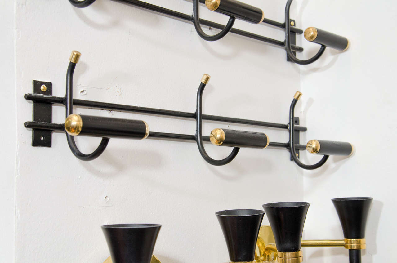 A vintage circa 1950s pair of French rare wall mounted coat racks or Porte-Manteau attributed to Jacques Adnet. Made of black enameled iron with brass accents.
Also available individually for $2900
