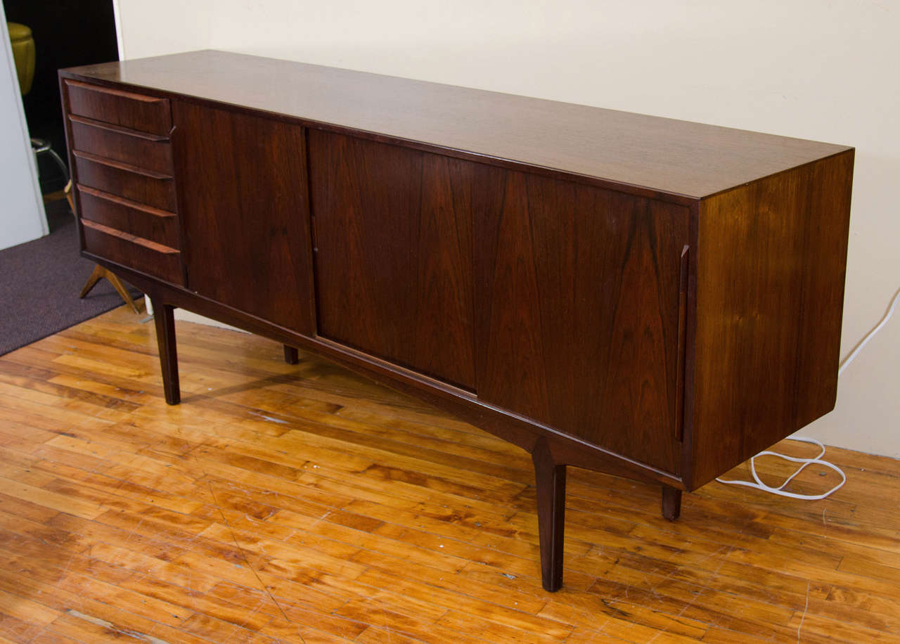 A vintage 1960's Scandinavian Rosewood credenza. It has five drawers, three sliding doors, and interior shelves.

7430