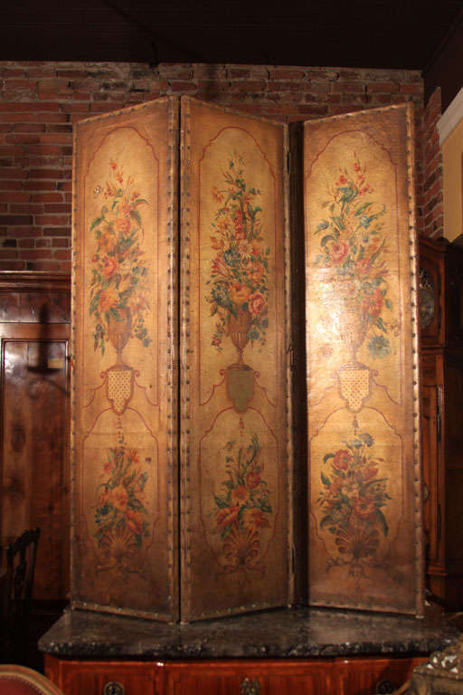French Hand-painted Three Panel Leather Screen.

This lovely decorative screen features earthy colors with floral designs.

The borders are trimmed with nail heads, original to the screen.

The back is covered in a salmon colored fabric which