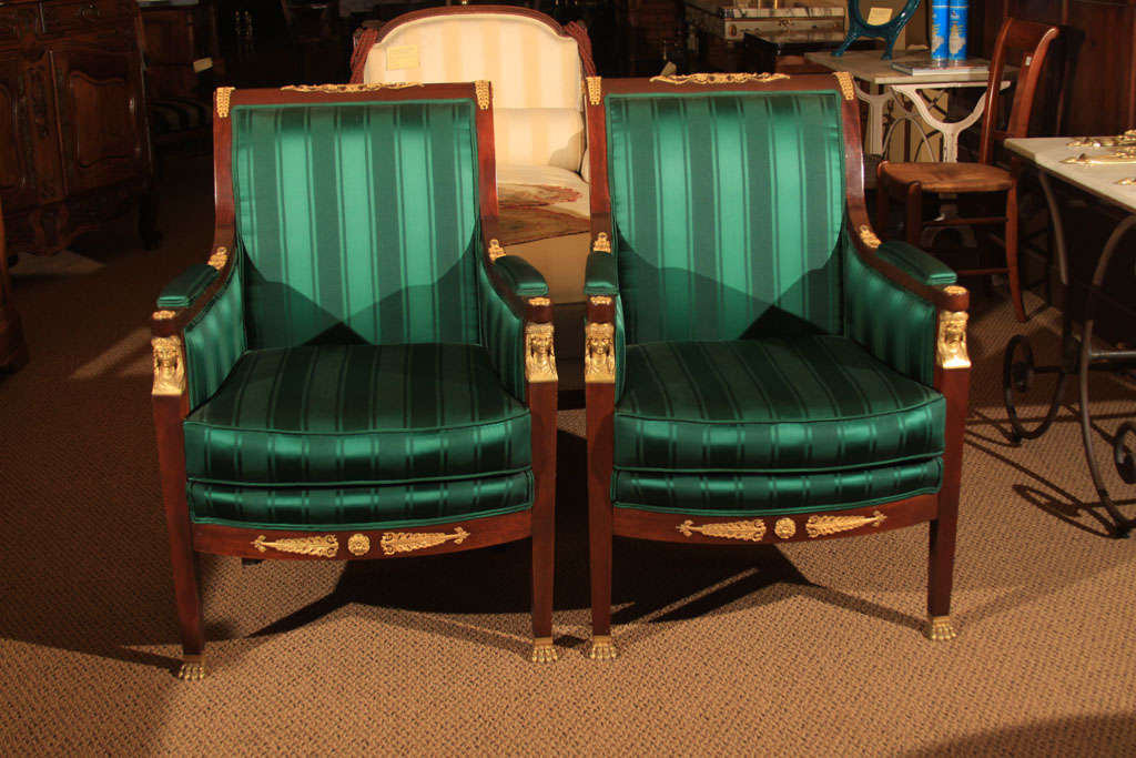 Striking Pair of French Napoleon III Mahogany Bergeres (Closed Arm Chairs) with original gilt bronze.<br />
<br />
Large scale and very comfortable seating.<br />
<br />
All of the gilt bronze dorie' is original right down to the lions paw