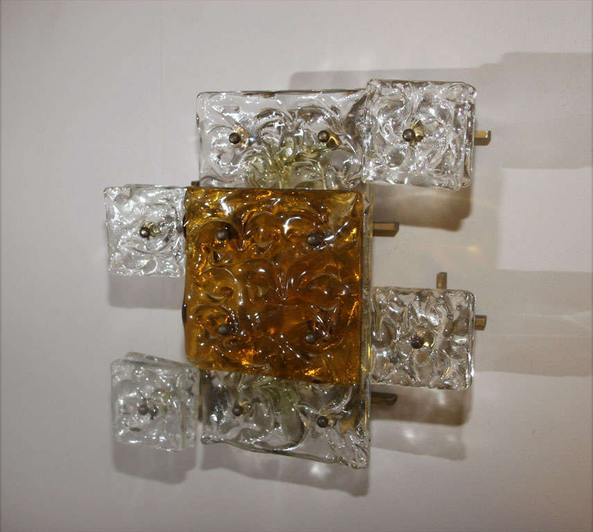 A pair of Italian modernist form sconces, produced circa 1950s, each with square panels crafted of clear and amber Murano glass, affixed to brass wall mounts.