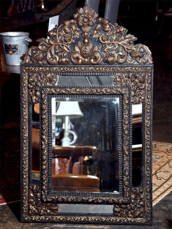 French brass repousse mirror, c. 1875, of pillow cushion form, and beveled mirror glass