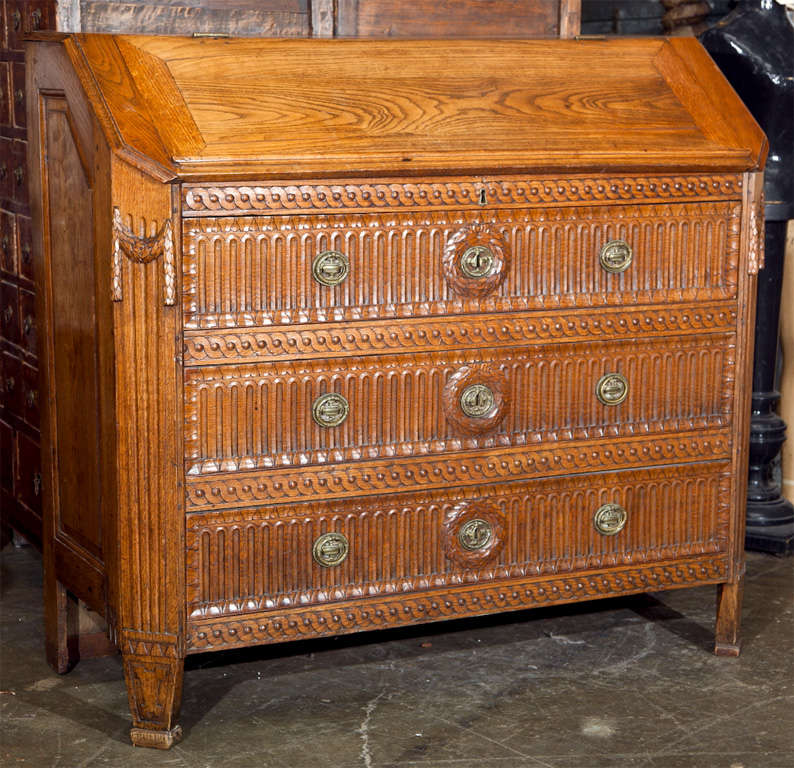 Danish elm secretaire, c. 1785, of the Gustavian period in the neoclassic style with appropriate caved motfs, three carved and fluted drawers over a fall front desk fitted with interior drawers.