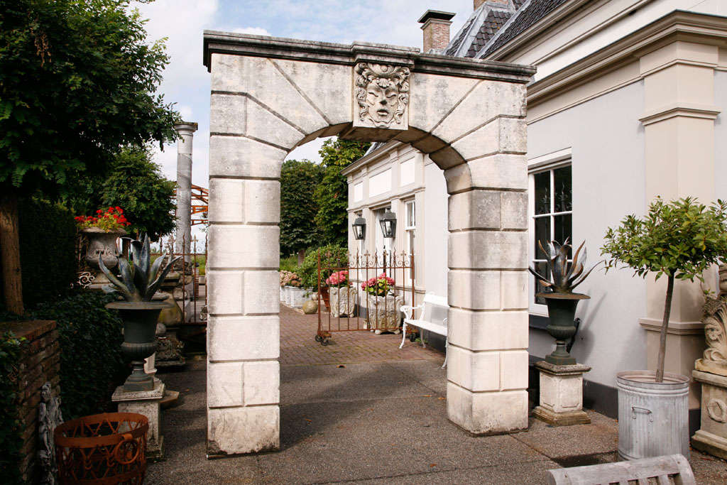 A carved limestone arch. The central keystone carved with a male mask to one side, a rosette to the underside and a female mask to the other side.