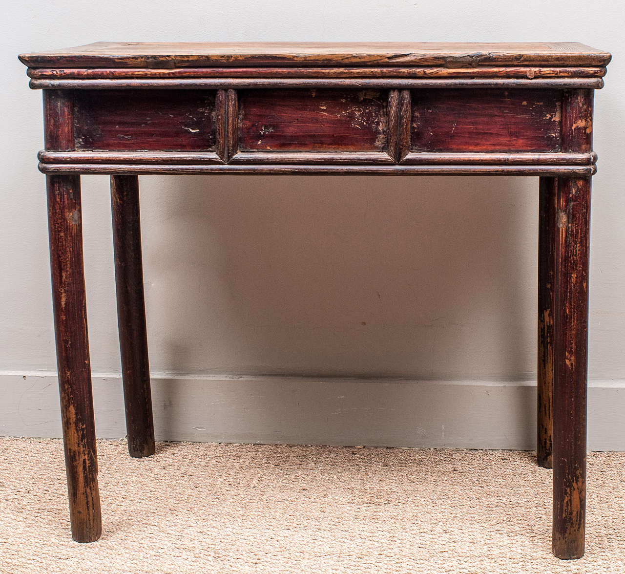 Three-drawer Chinese elmwood desk retains slight remnants of its original red lacquer finish. The top of the writing surface glows with a mellow patina.