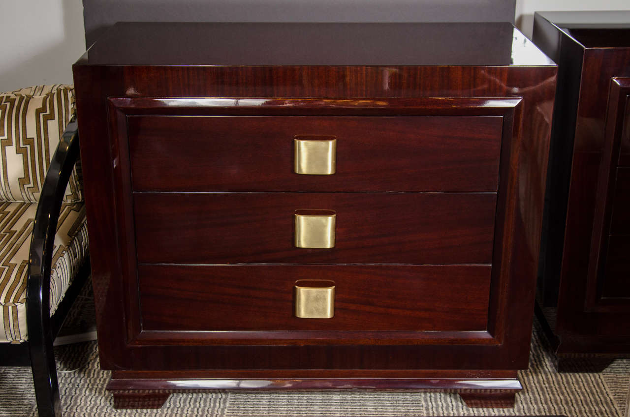 This pair of outstanding Mid-Century Modern chests in bookmatched mahogany feature a frame design and features three large deep drawers providing ample storage. Each drawer has a streamlined brushed brass bowed design pull. Restored to mint
