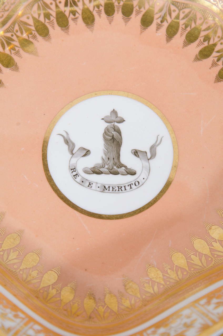 The crest of the family of Phipps* with the motto: Re E Merito emblazoned in grisaille on this pair of George III/IV porcelain dishes by Spode, circa 1820. The armorial is centered on a shell shaped dish with peach ground decorated with lavish