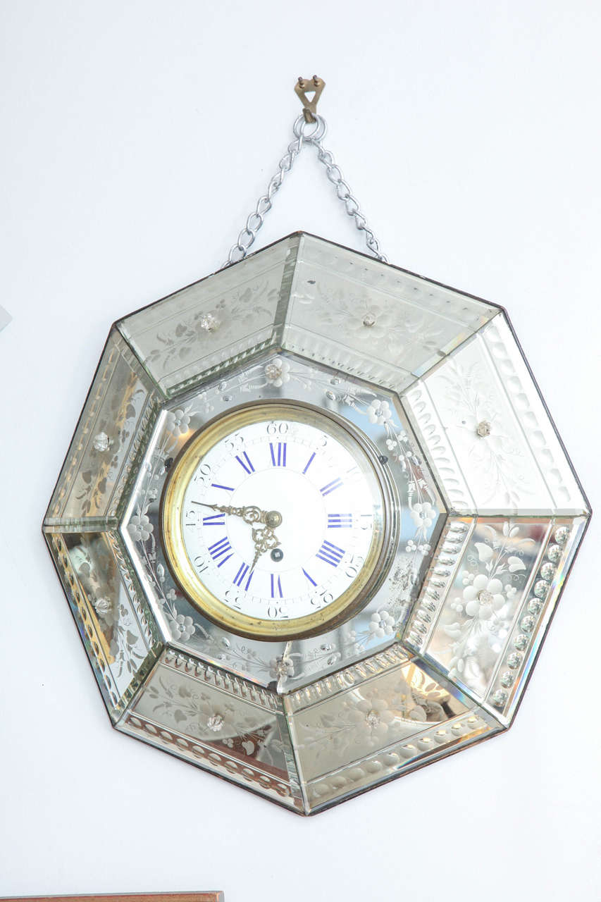 This wonderful clock is set in etched mirrored panels, forming a hexagon. It hangs from a chain.