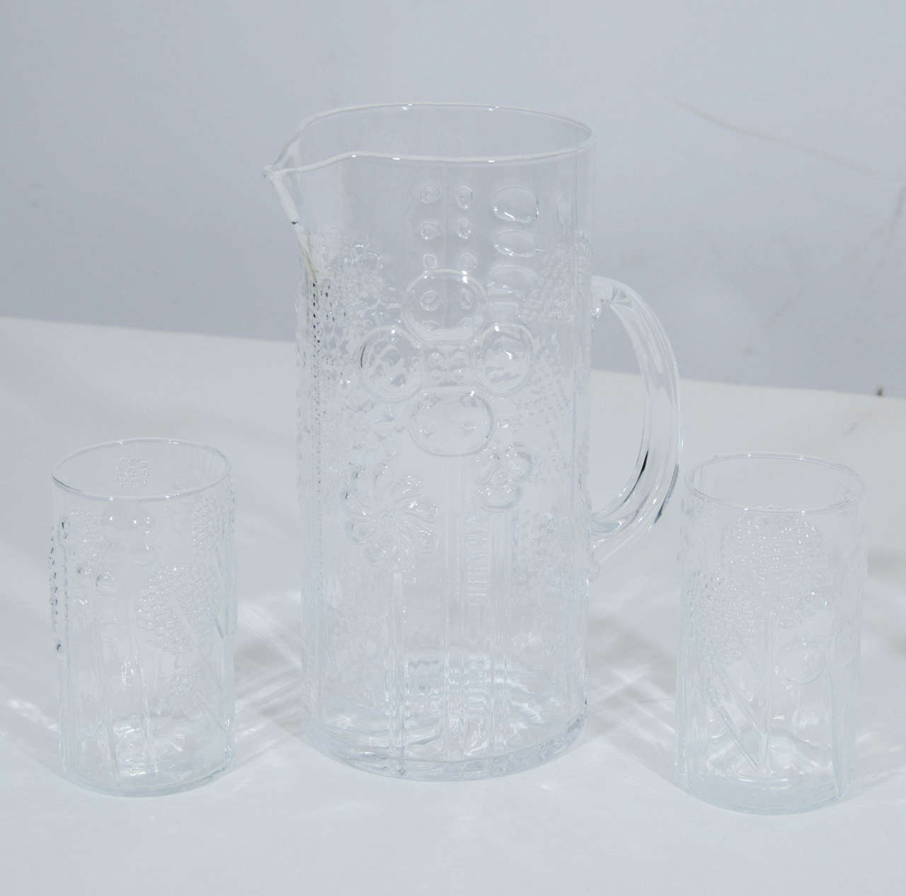 Beautiful and charming crystal pitcher and six glasses in the Flora series by Oiva Toikka. Dimensions below are for pitcher; the dimensions of each glass is 4.38 height x 2.5 diameter. Glasses are handblown and dimensions vary slightly. Please