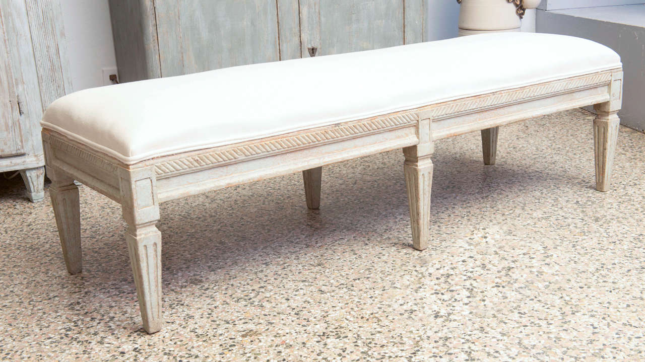 Swedish Gustavian period upholstered bench with moulded apron above six tapered square legs: upholstered in off-white linen.