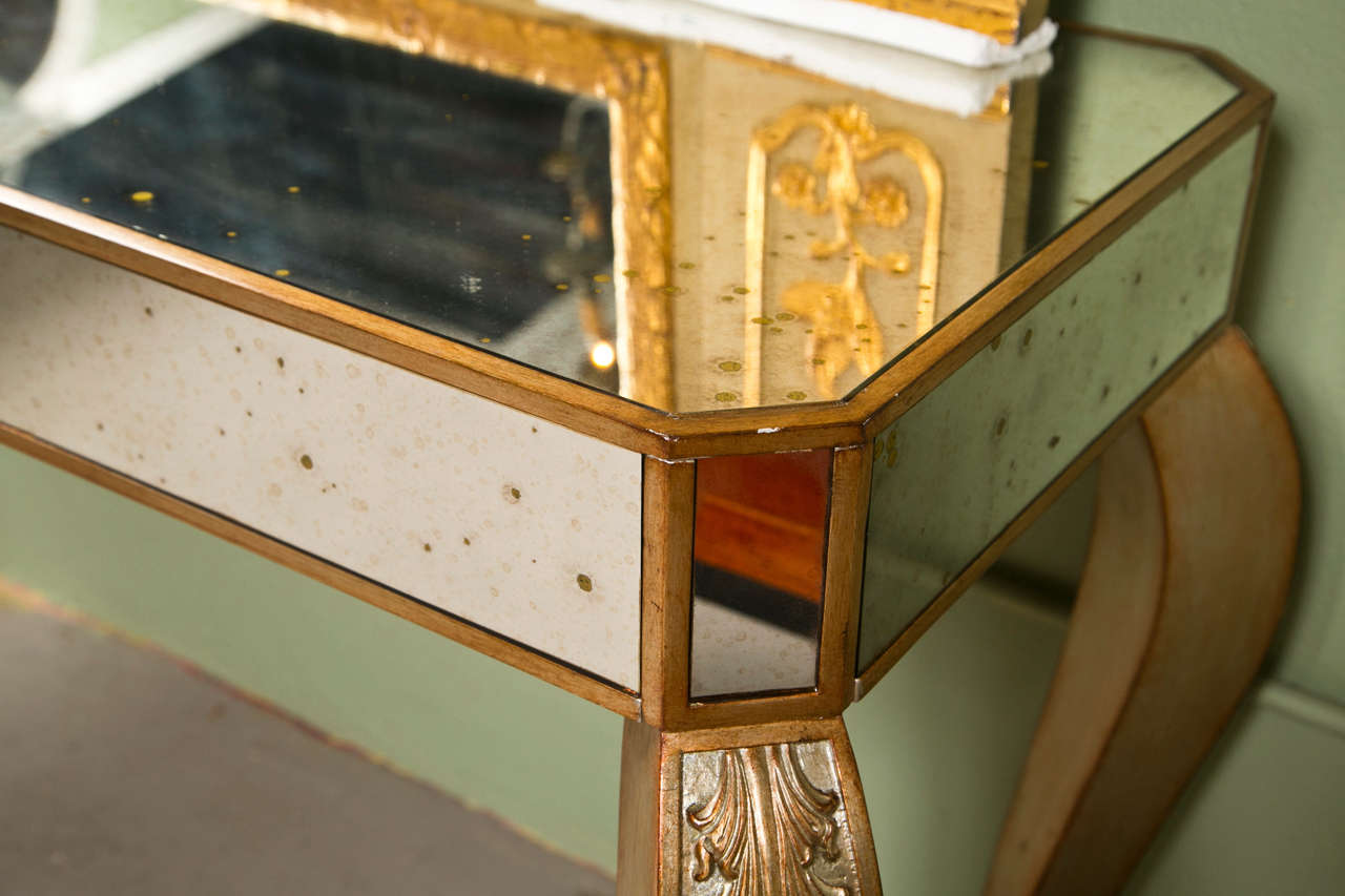 Une élégante console décorative, cadre doré, plateau en placage de miroir équipé d'un seul tiroir, reposant sur des pieds en carbiole surmontés d'une sculpture feuillagée.
