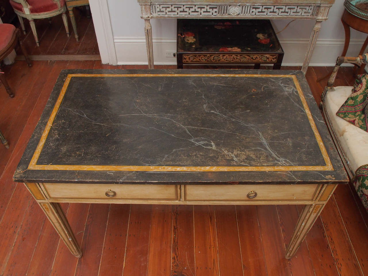A two drawer desk or writing table with a faux marble painted top over tall, square tapered legs.