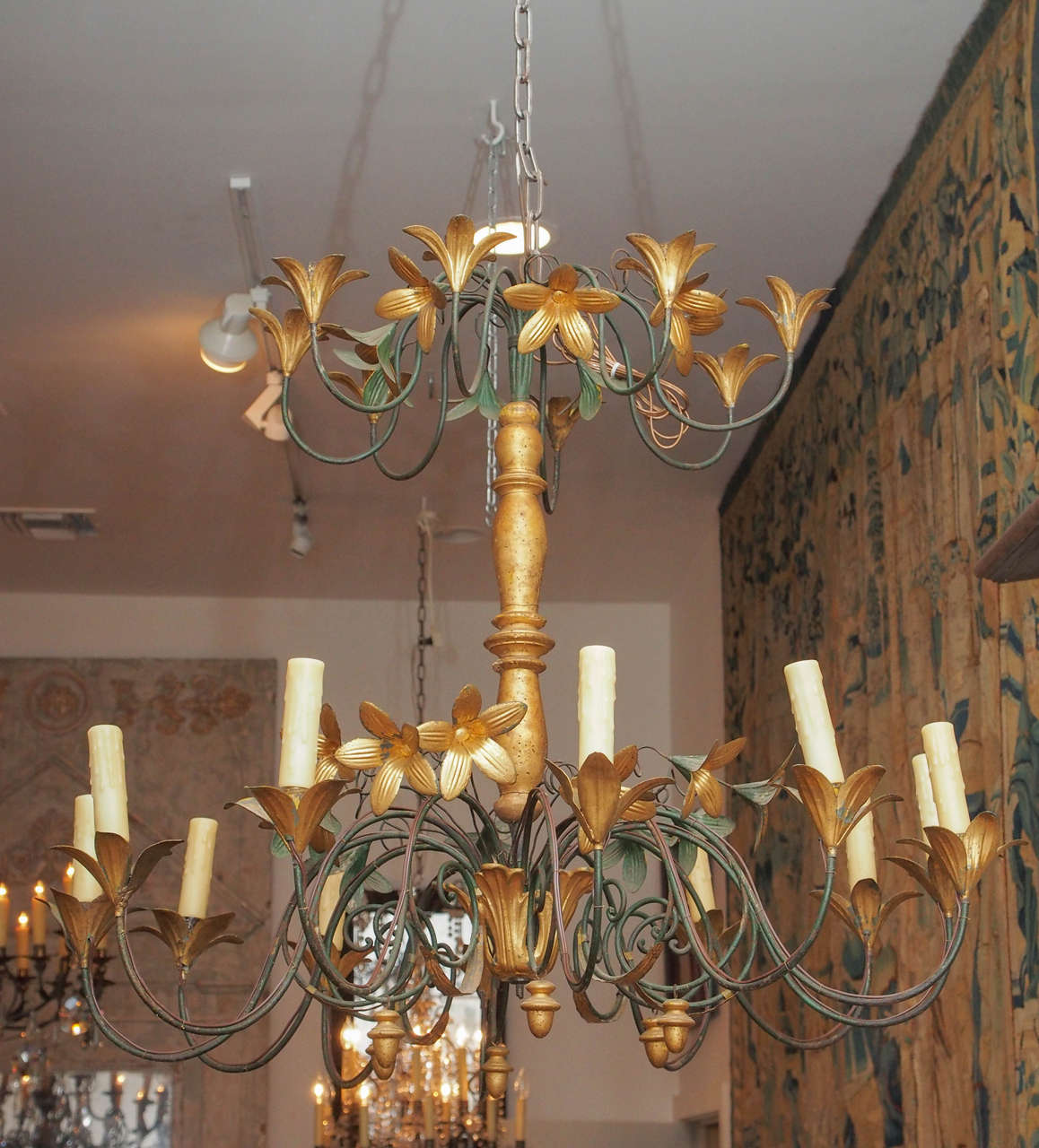 A 19th century gilt iron and tole chandelier with a turned and gilded central support, iron arms and tole flowers. Having two tiers of candle holders, on the lower tier wired.  Acorn shaped gilded finials suspended from the lower arms.