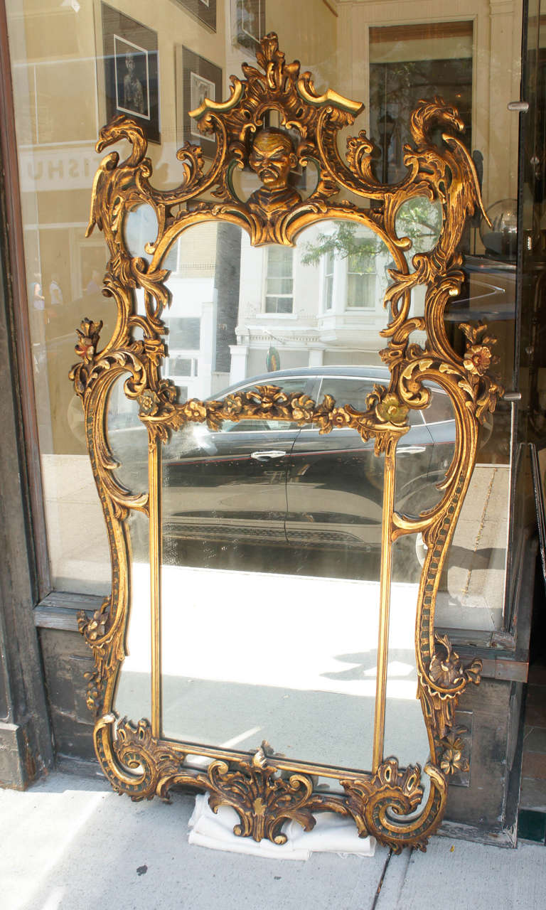 This fine vintage mirror made in the Chinese Chippendale style is crafted from carved and gessoed wood then gilded with matte and burnished gold. It was then antiqued with some areas of glazing and polychroming creating a dramatic and very