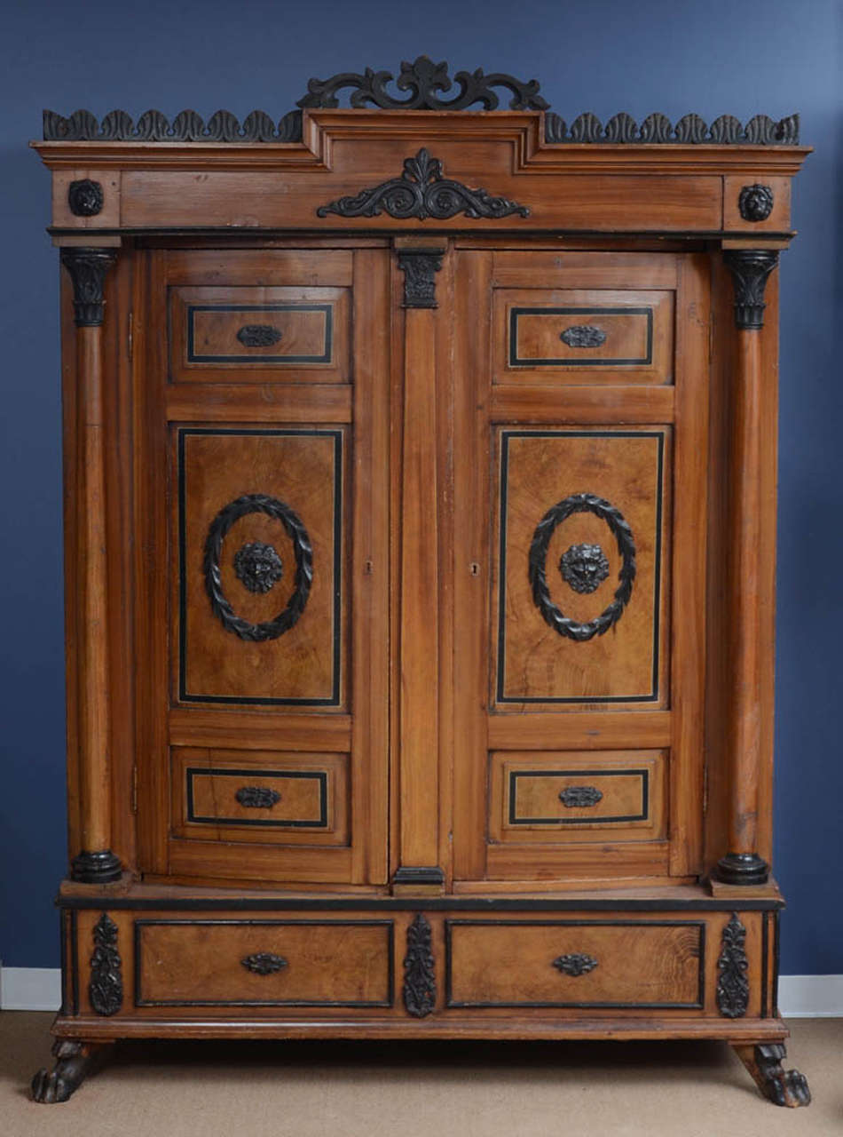 This very good armoire made circa 1820 is paint decorated in an overall wood grain pattern that includes long strait graining and burl graining. The carved and neoclassical elements are painted black making the whole a dramatic commanding form.