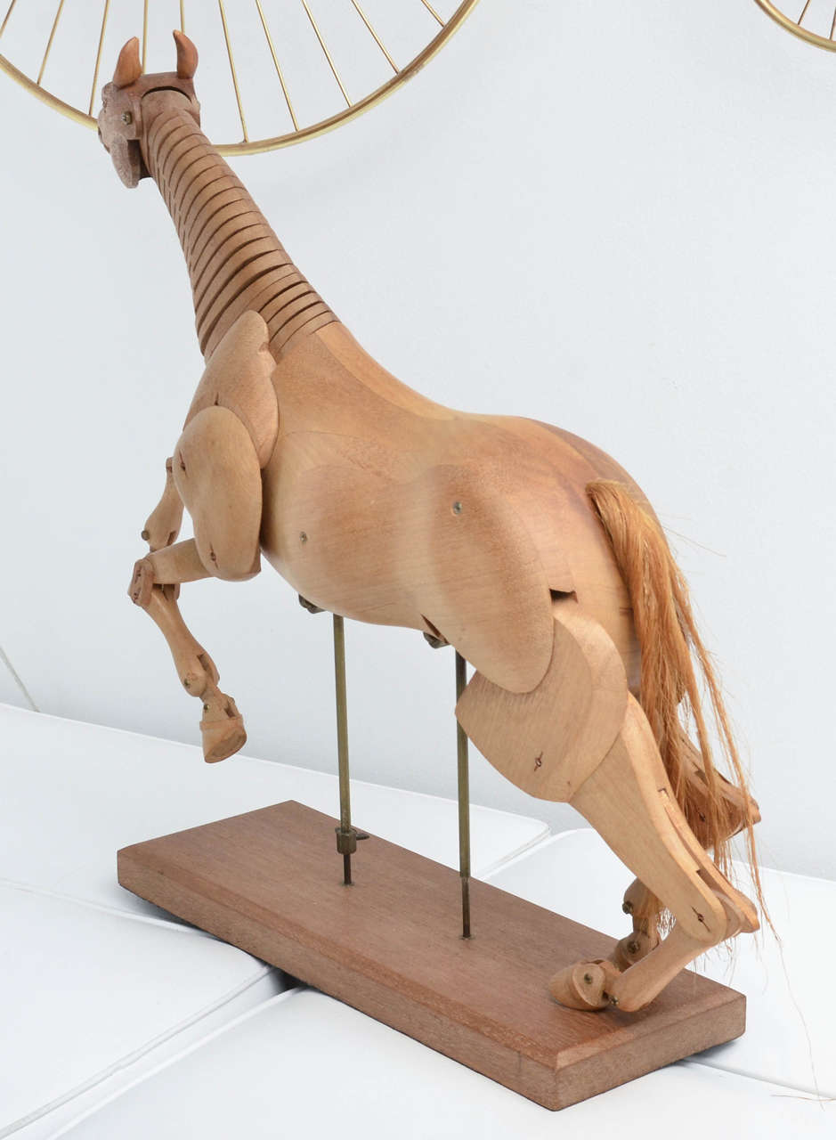 Wooden flexible model horse mounted on stand.