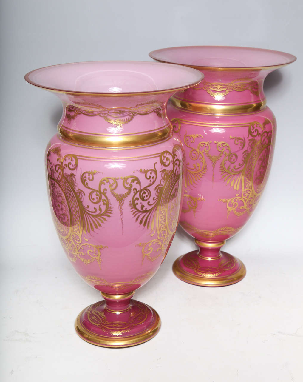 A pair of exquisite and large antique French Louis XVI pink opaline gilt decorated vases of fine workmanship adorned with hand painted gilt panels depicting floral motifs by Baccarat, Paris, circa 1870s.