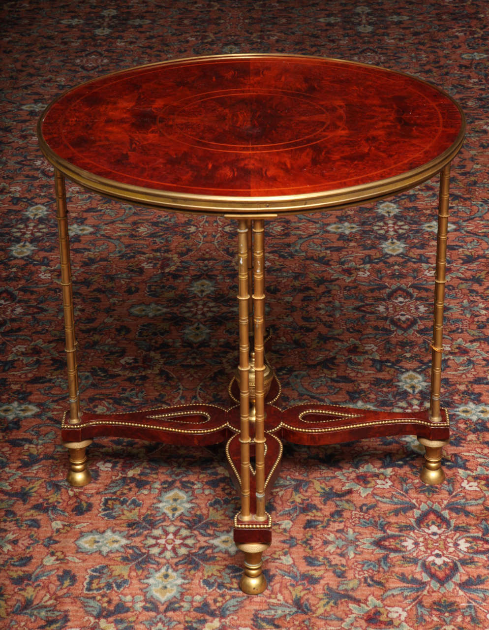 A unique antique French Louis XVI gilt bronze mounted mahogany guéridon of fine detail embellished with eight gilt bronze bamboo legs and further adorned with a reticulated gilt bronze mounted stretcher with a central gilt bronze urn, after a model