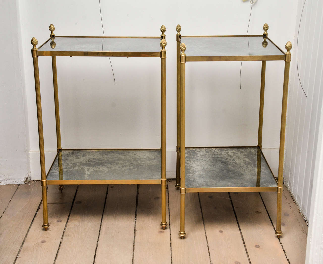 Pair of aged patina brass with mirrored glass end tables with two shelves and acorn finials.
