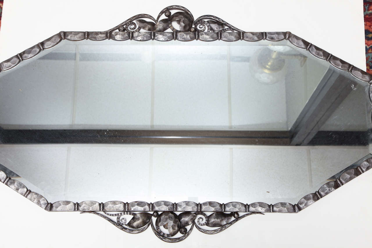 Art Deco Mirror, French, 1930s, in the manner of Nics Freres,
of octagonal shape, hammered wrought iron with foliate and scrolled decoration and beveled plate.
Width 46 1/2 inches, height: 26 1/4.