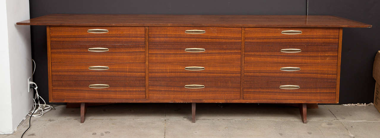 Large chest of drawers, model OH-212-W, walnut with brass drawer pulls. Overhanging top on plank leg base. Burn mark in drawer, George Nakashima, and Widdicomb paper label.