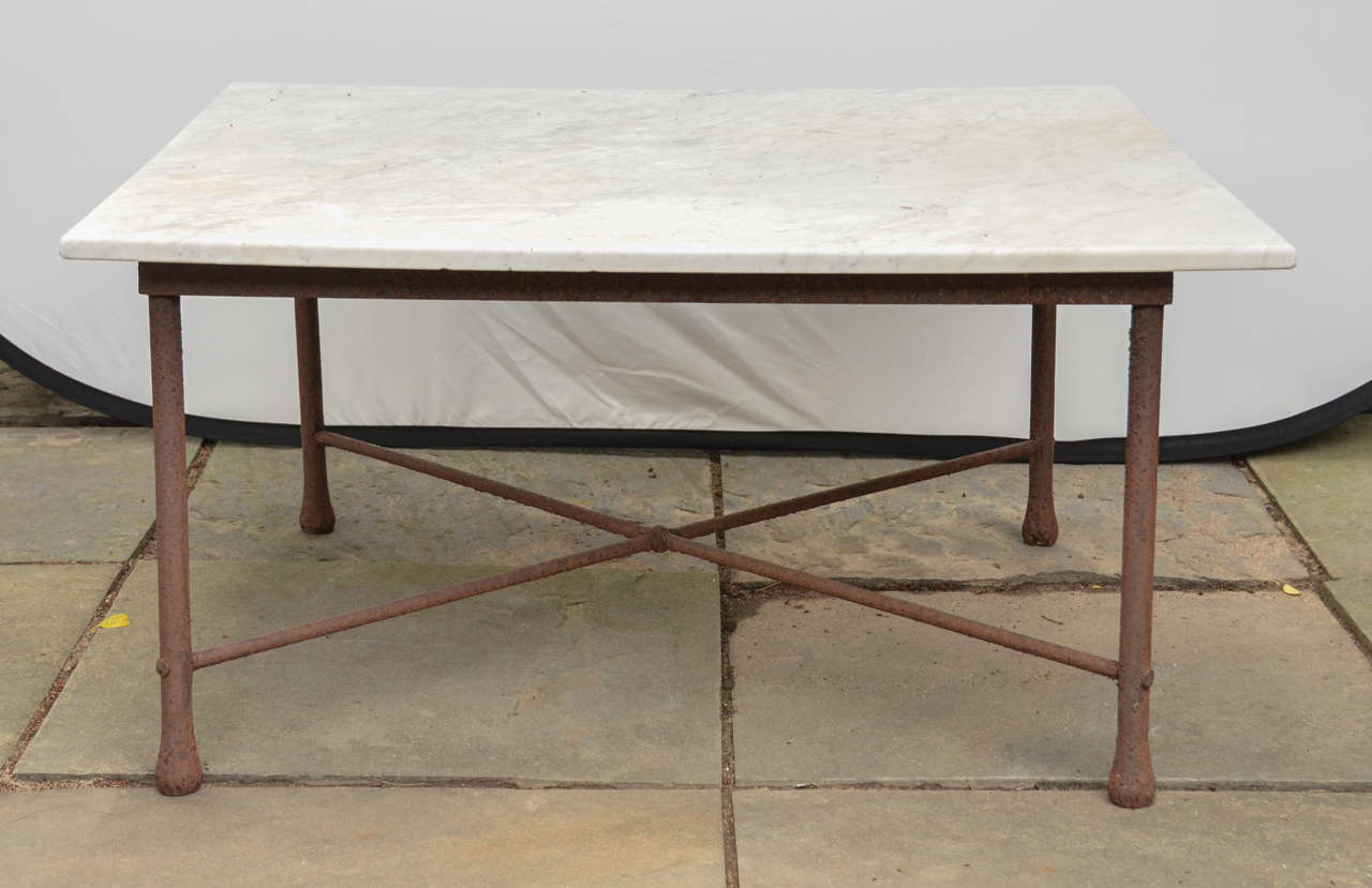 American 1970s Wrought Iron Coffee Table With Marble Top. Base Has Four Circular Legs With Larger Rounded Bottoms. The Legs Are Joined By An 