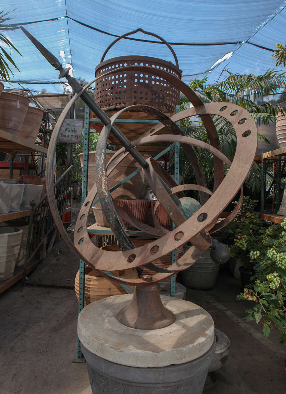 Armillary sphere on stone base, made mostly of 19th century pieces. The base is from a grinding and sharpening stone from the mid-19th century. The rings are from 19th century wagon wheels. The outer ring with the holes is also from a 19th century
