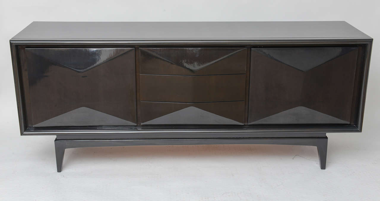 Exquisitely finished raised diamond front ebonized floating credenza. Finished inside and out with three center drawers flanked by two doors each revealing an adjustable shelf and a stationary bottom shelf. The drawers and doors open by hand grip