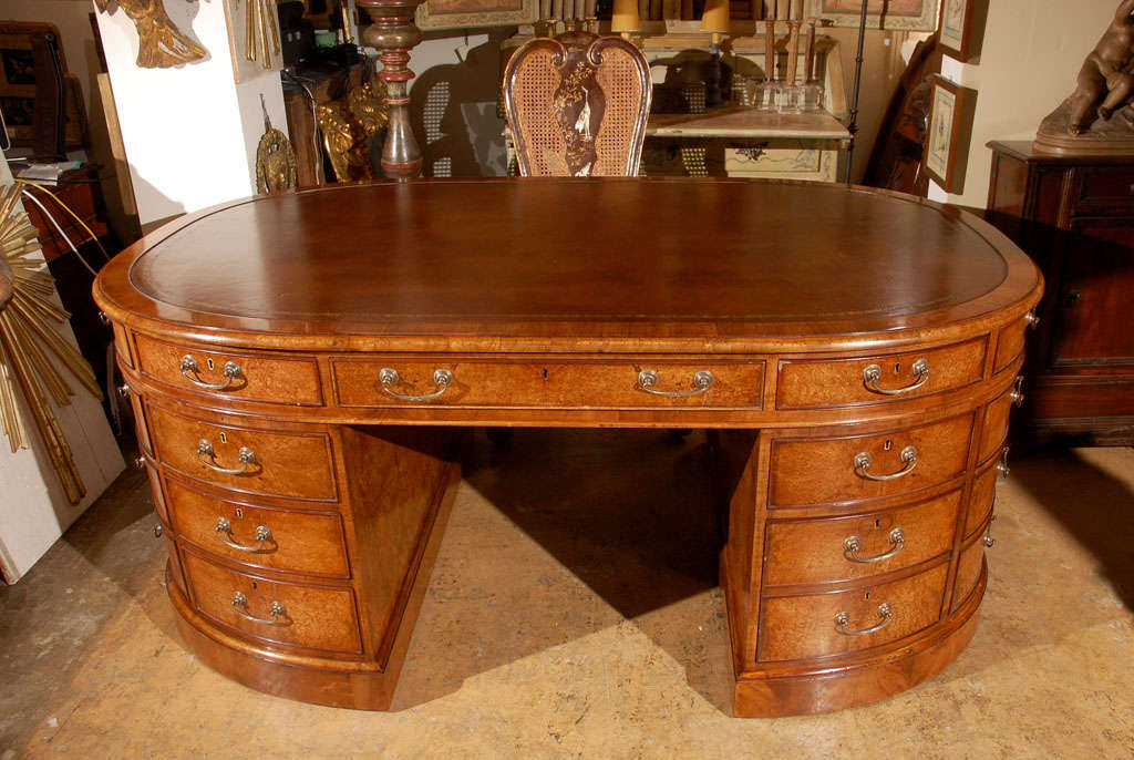 Oval, embossed leather-top partners desk with gold banding and nine functioning drawers each side.