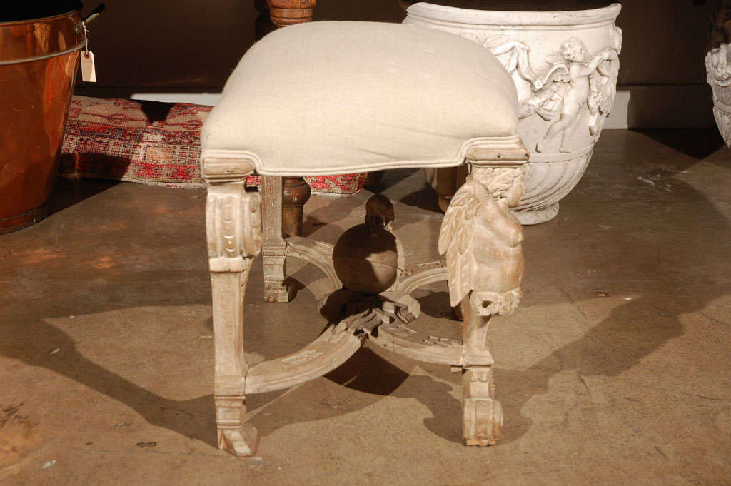 Elaborately carved, white-washed, wood stool featuring cherubs and a central globe surmounted by a dog.