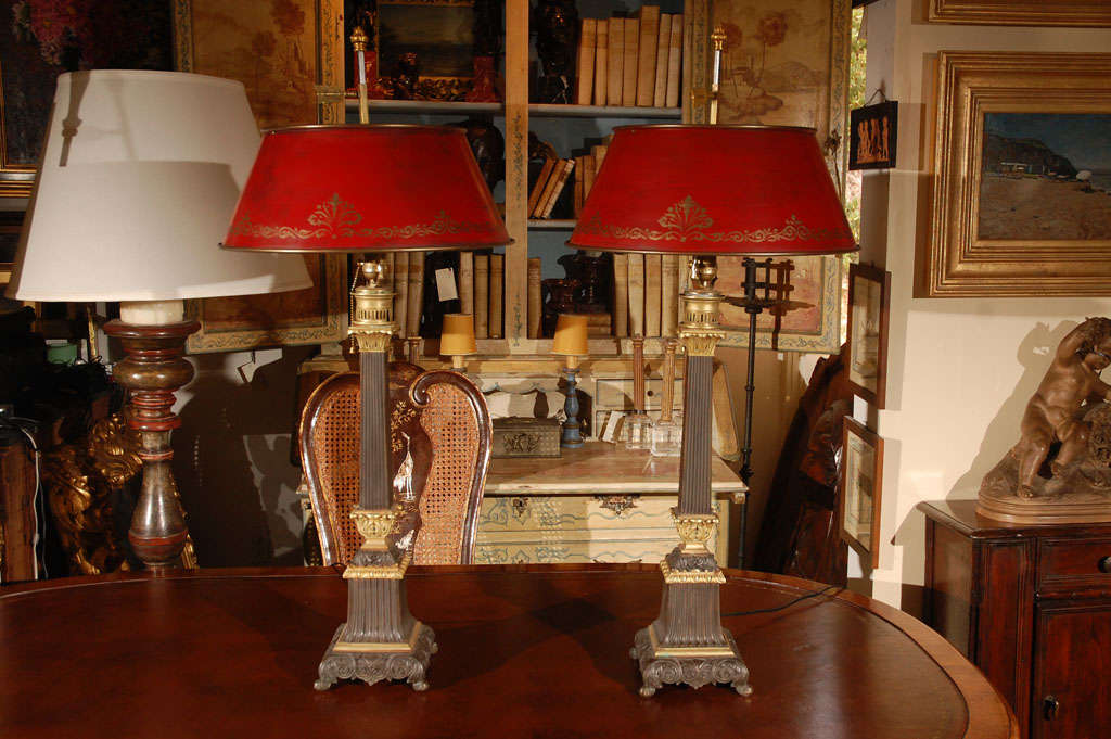 Pair of bronze column lamps with red tole shades.