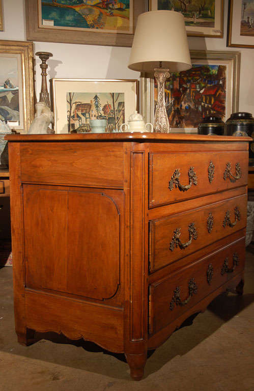 Three drawer walnut commode hand cast bronze handles and lock surrounds, paneled sides and a scrolling apron.