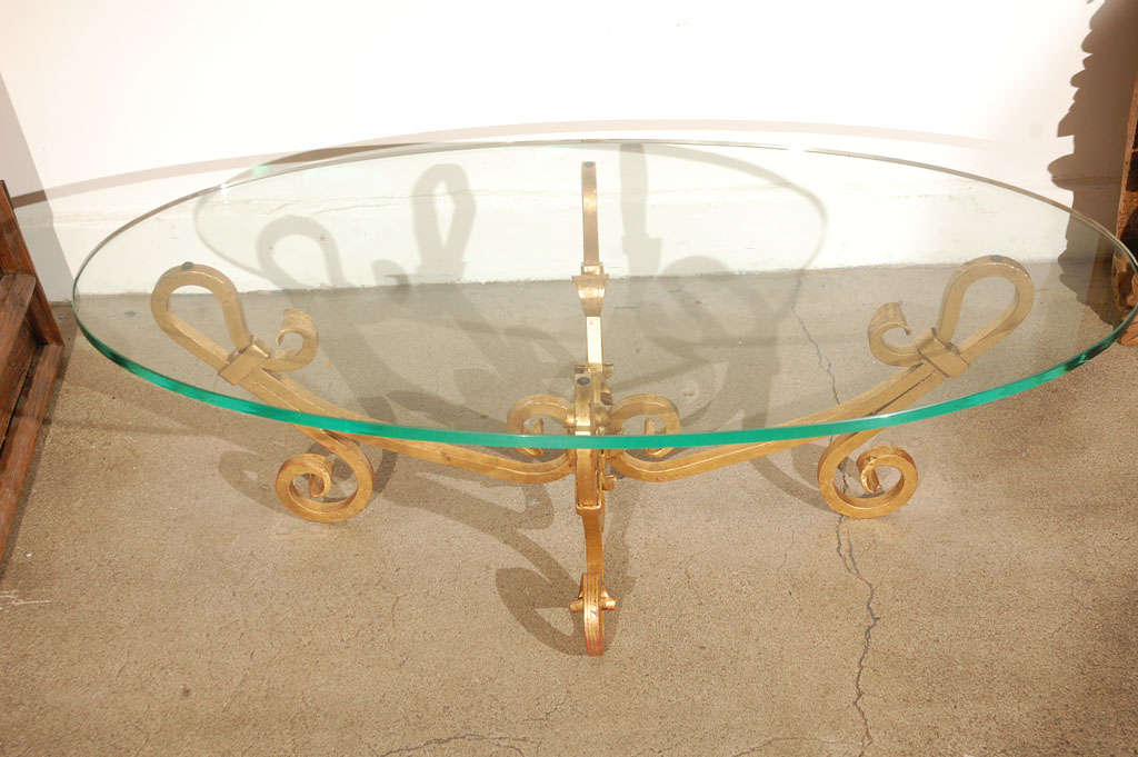 Elegant oval glass and gilt iron coffee table, Italian Venetian style.
Hand-forged gilded iron base with oval glass top, cocktail or coffee table. 
Thick 3/4 inch bevelled glass top in good condition.
Hand crafted in Italy.
Size: 24 in.  x 48 in  x